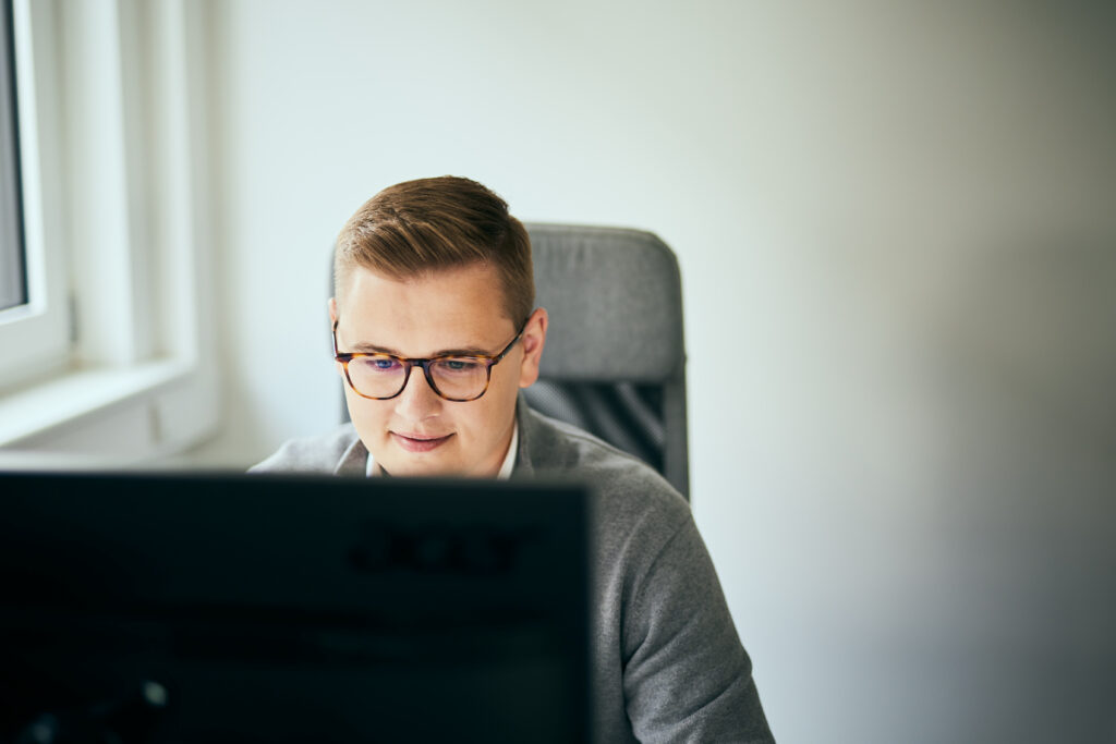 Foto von einem Mann mit Brille, der in einen Computerbildschirm schaut.