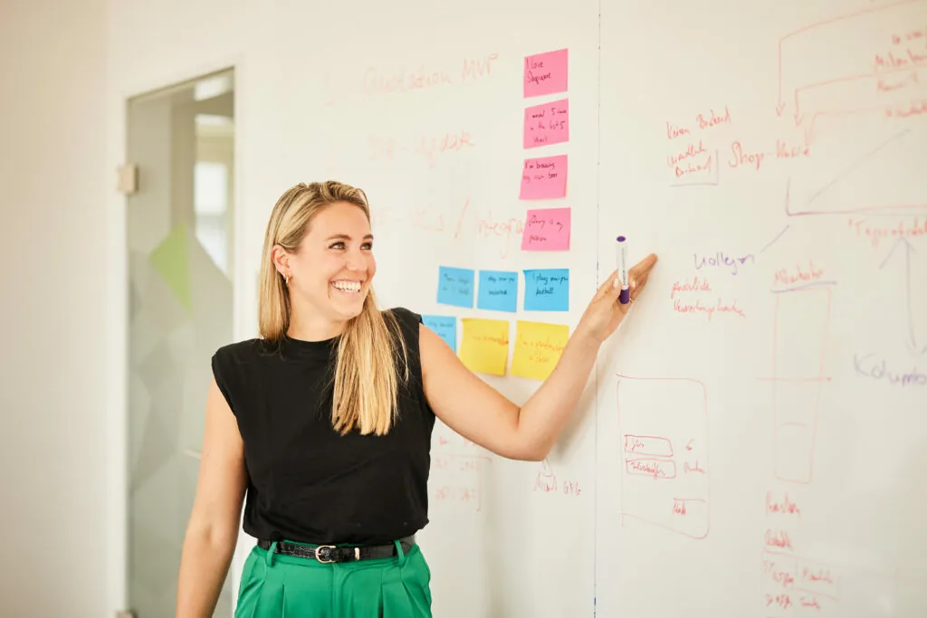 Foto von einer Frau, die ihre Strategie an einem Whiteboard erklärt.