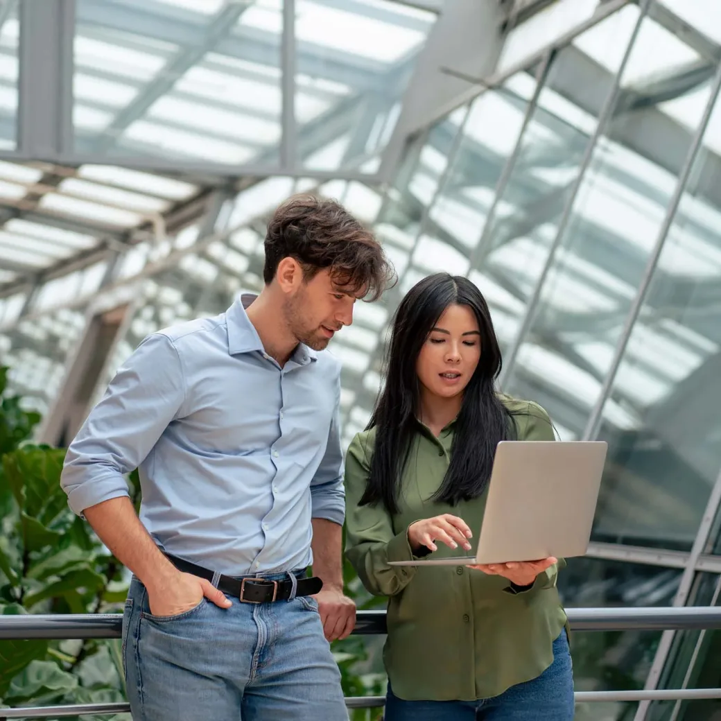 Businesswoman sharing laptop with colleague working in corridor