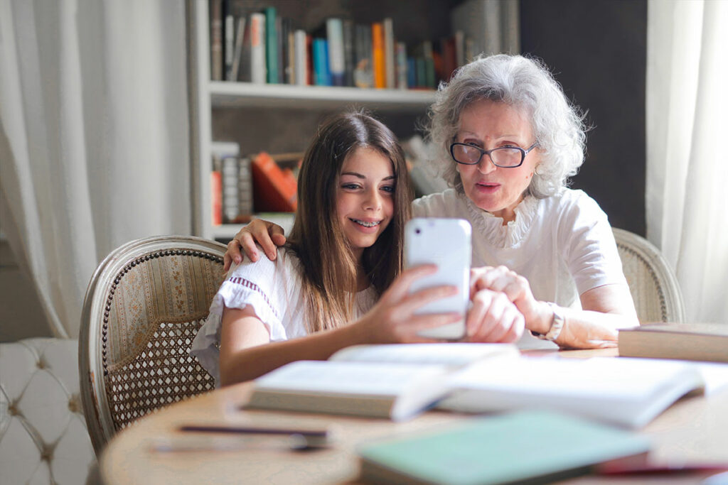 A granddaughter and grandmother are using an EAA-compliant platform or an accessible online shop on a smartphone.