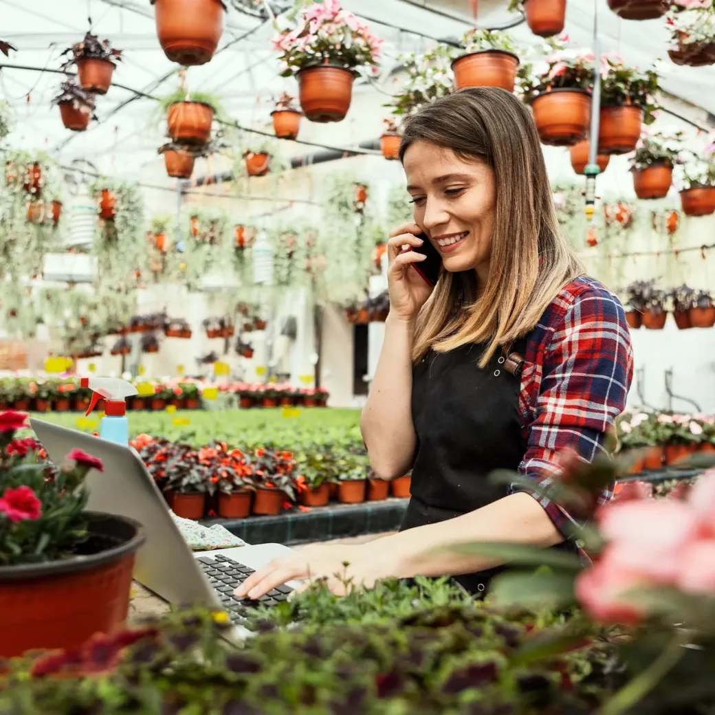 Florist looking at the laptop and writing down customer orders