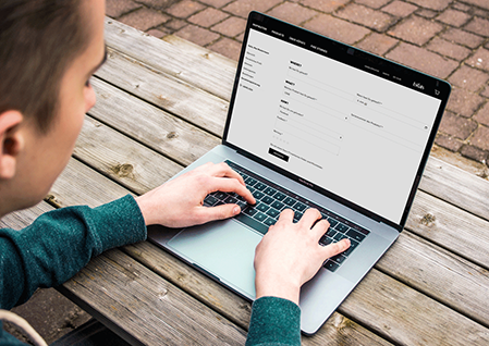 A person looks at a laptop while moving their hands over the keyboard.