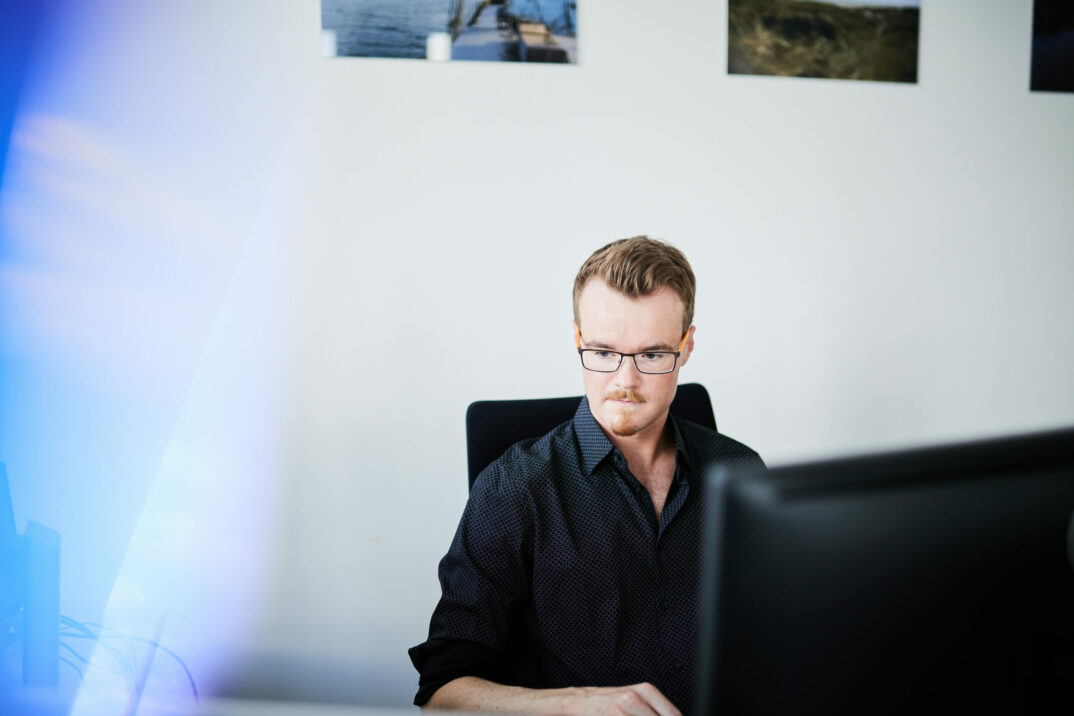 Bild von einem jungen Mann, der vor seinem Computer sitzt und an einer CX-Wesbite-Strategie arbeitet.