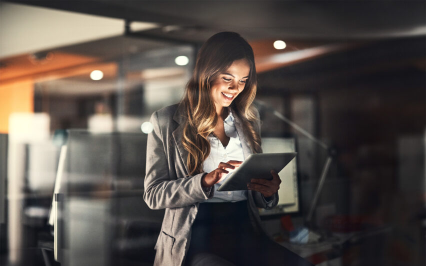 Cropped shot of a young attractive businesswoman using a tablet while working late at night in the office