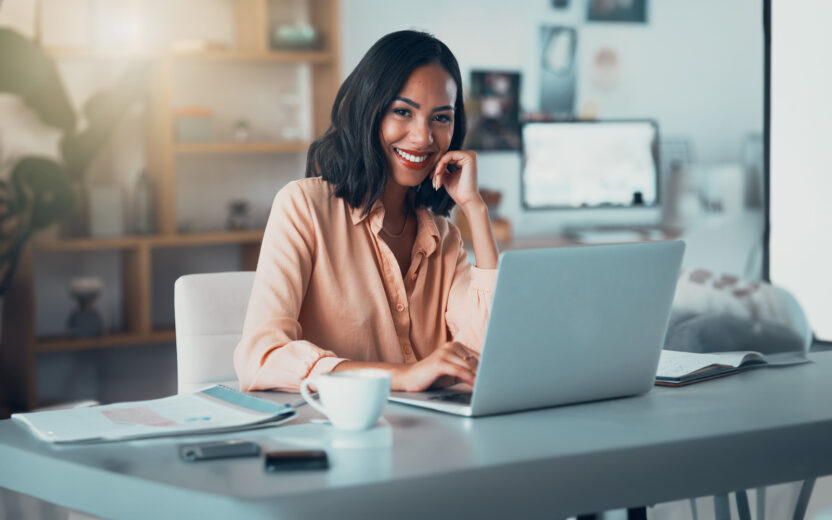 Portrait of a happy business woman working on her laptop at a desk in the office