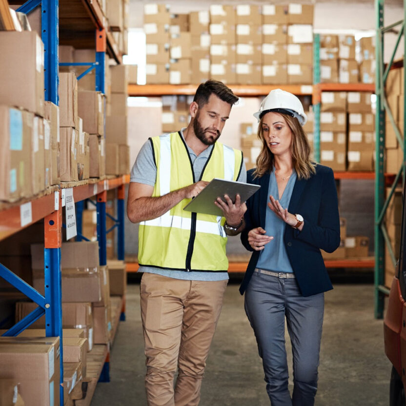 Cropped shot of an attractive young businesswoman walking through a warehouse with a male worker