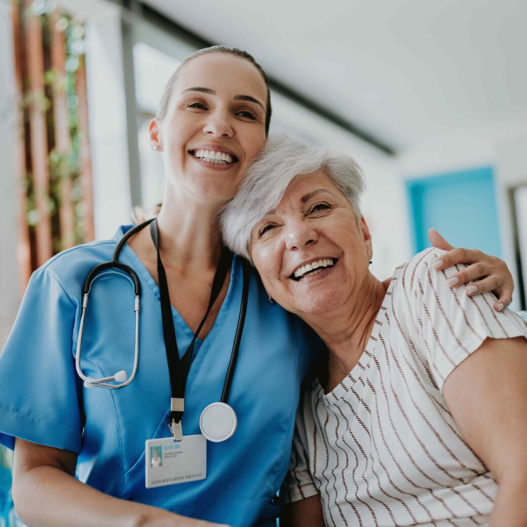 Home carer hugs elderly patient.