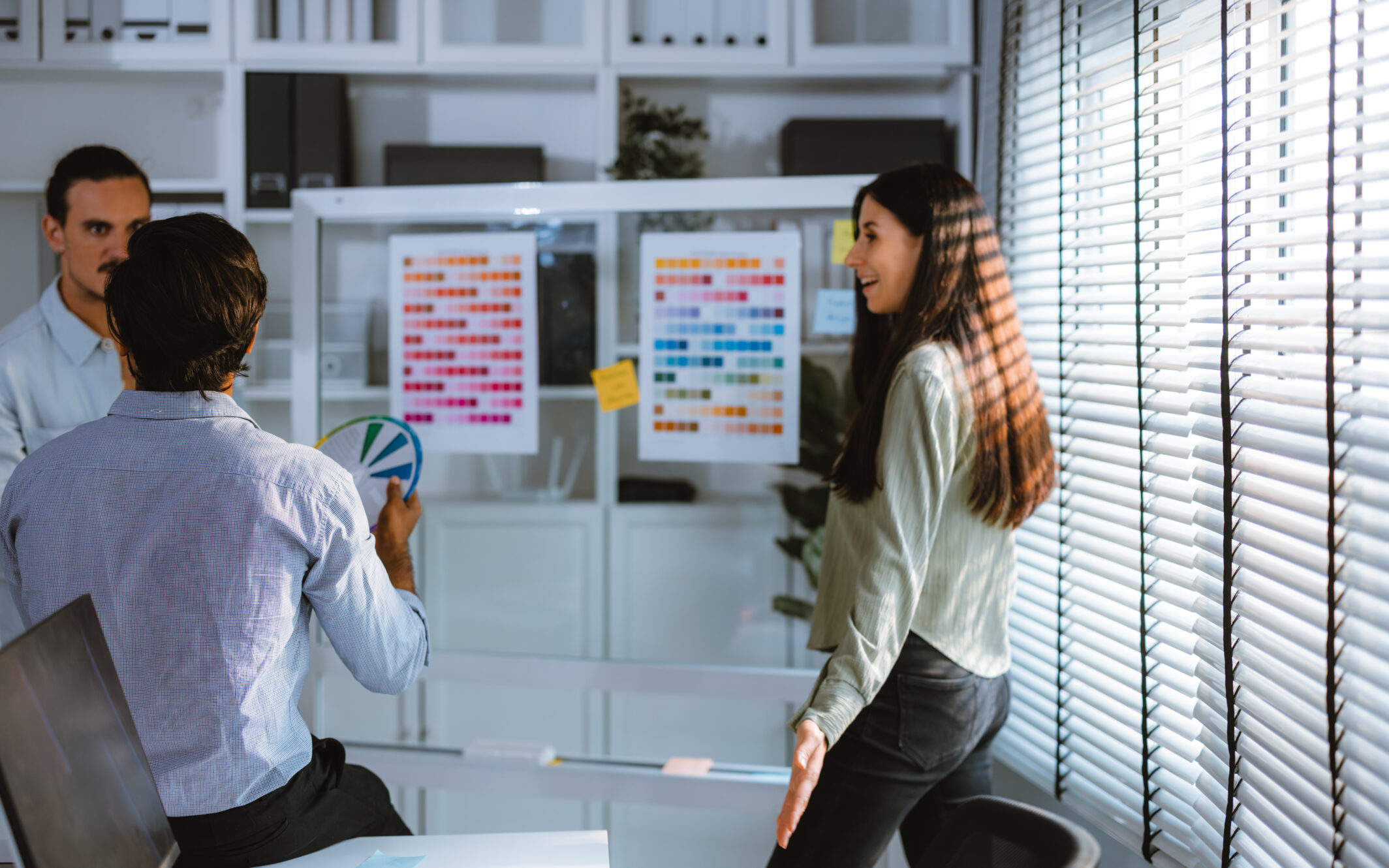 A team of young business people look at a color printout pasted on a flipboard and discuss user-centric product development.