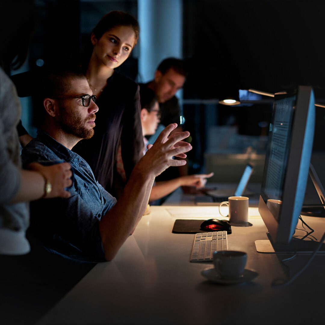 Shot of a group of colleagues using a computer together during a late night at work