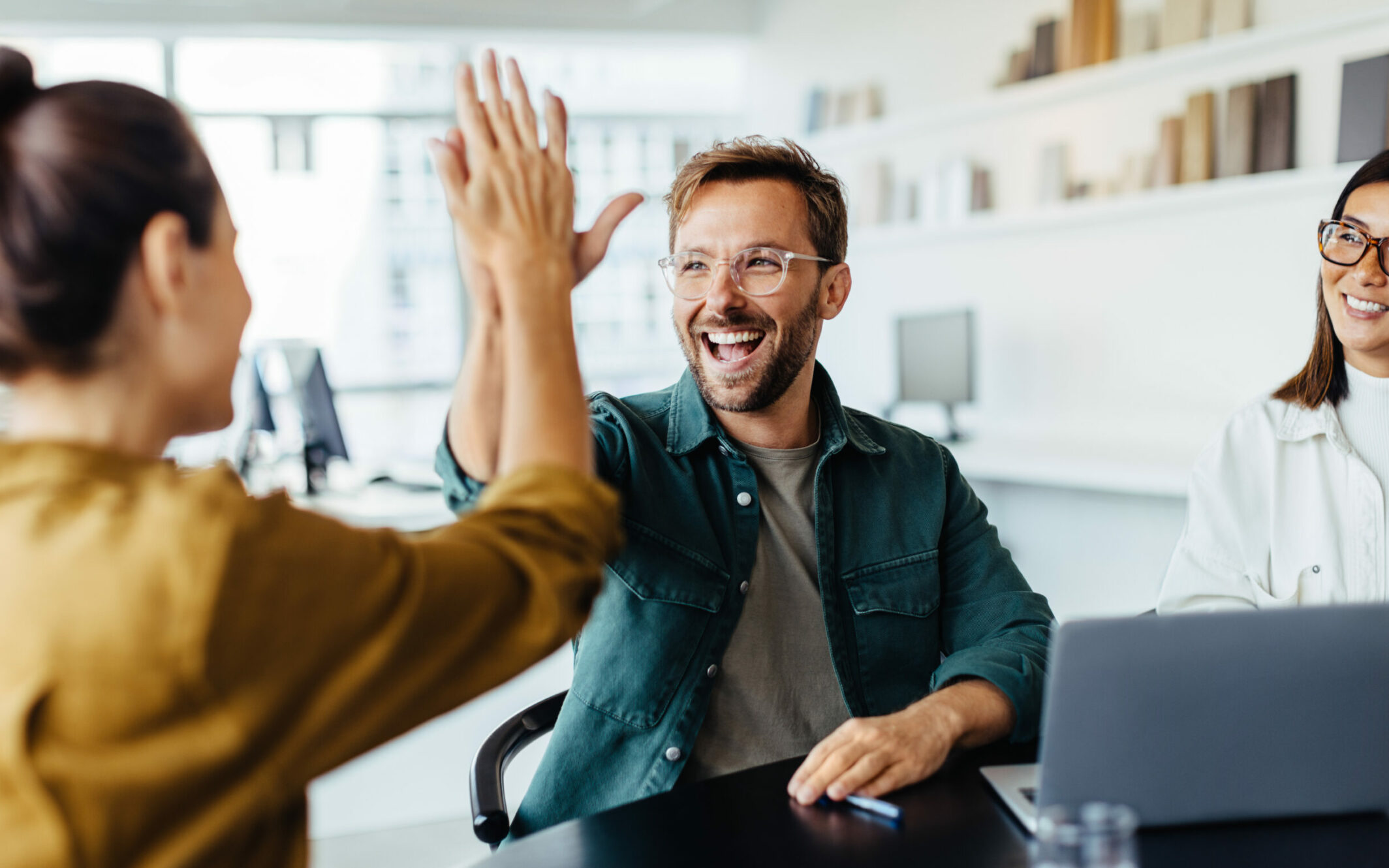 Zwei Arbeitskollegen geben sich gegenseitig einen High-Five und strahlen positive Gefühle aus.