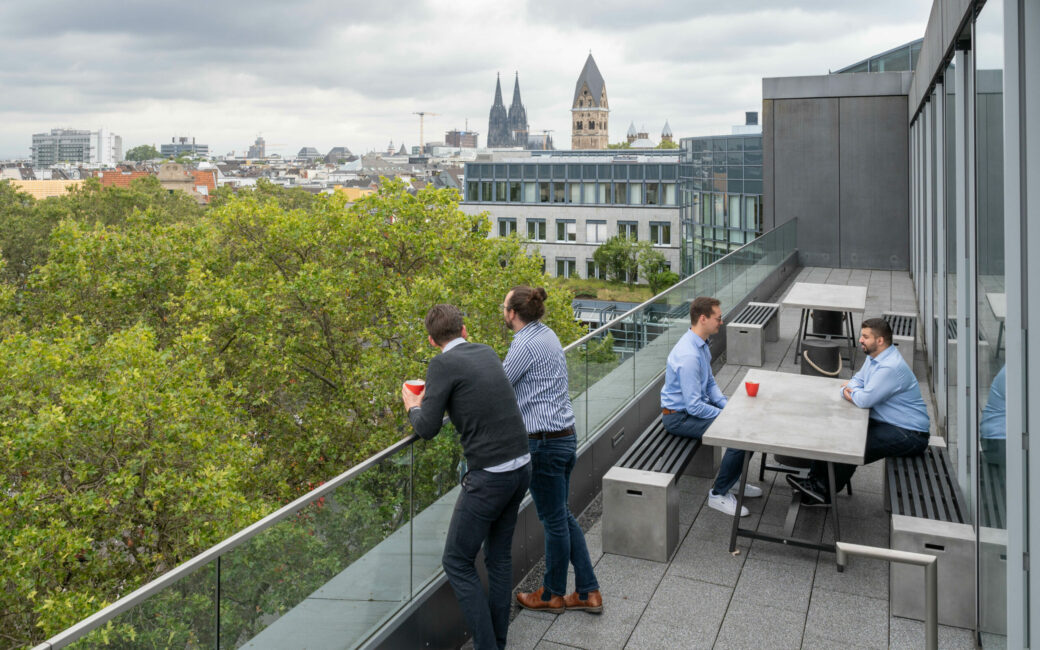 Mitarbeitende auf Dachterrasse genießen den Domblick im valantic Büro Köln Innenstadt