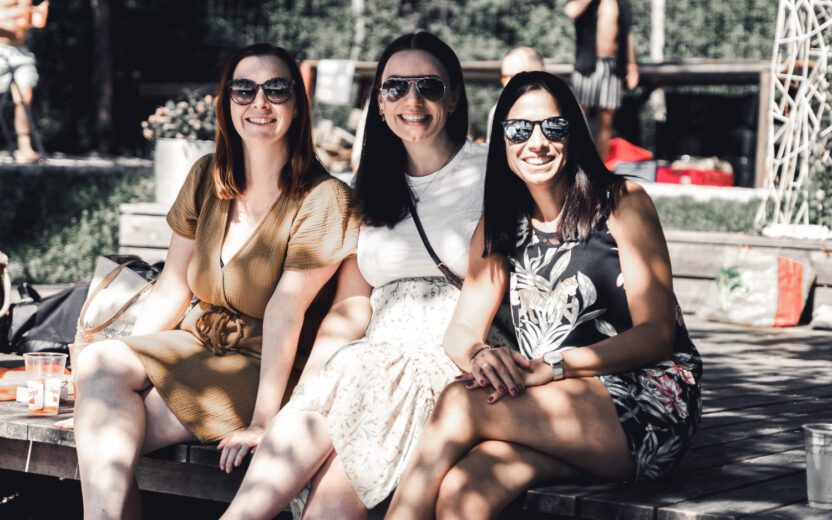 Drei lächelnden valantic Austria Mitarbeiterinnen in der Sonne mit Sonnenbrille.