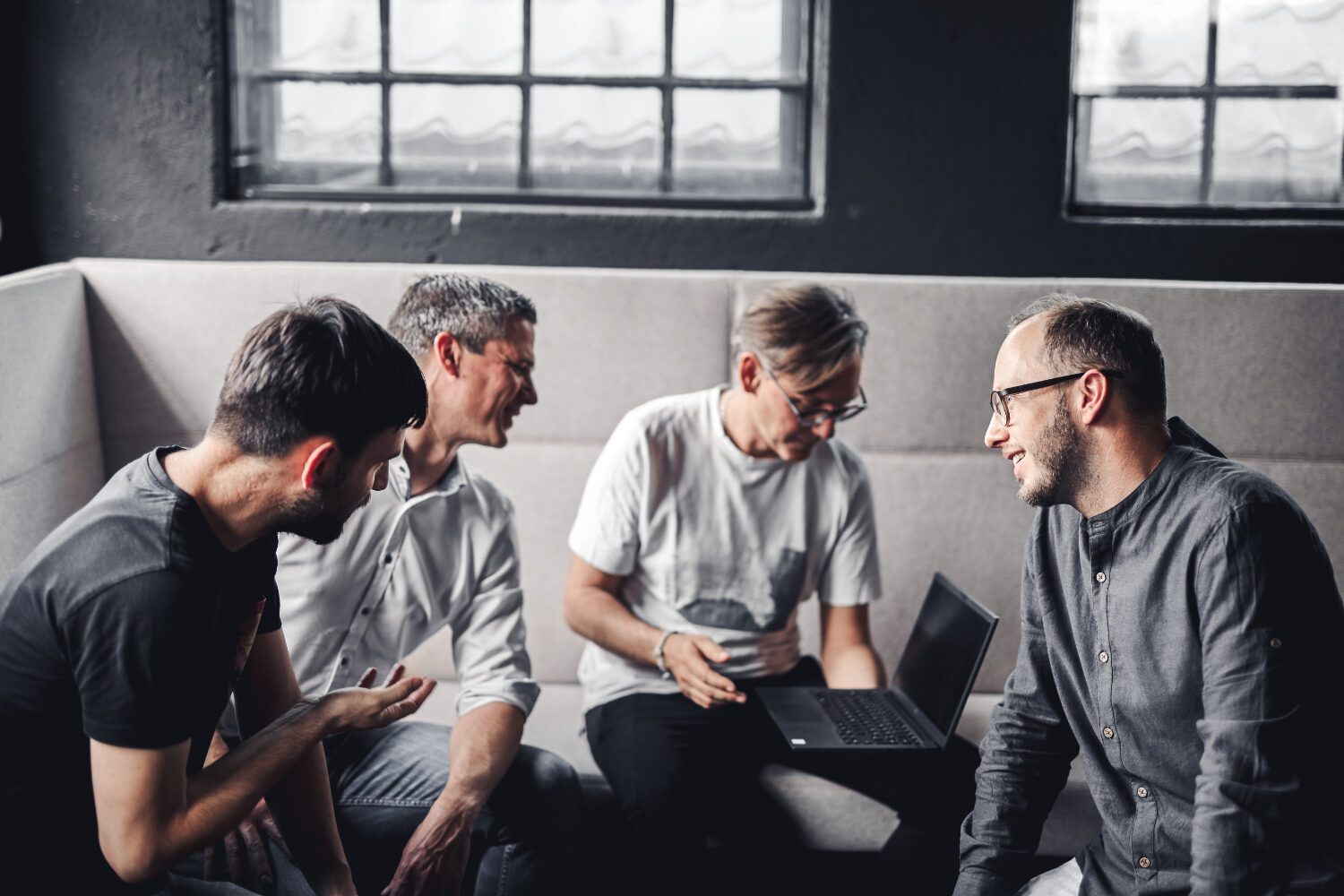Vier valantic Austria Mitarbeiter sitzen zusammen um einen Laptop und diskutieren eine neue Produktstrategie für einen Kunden.