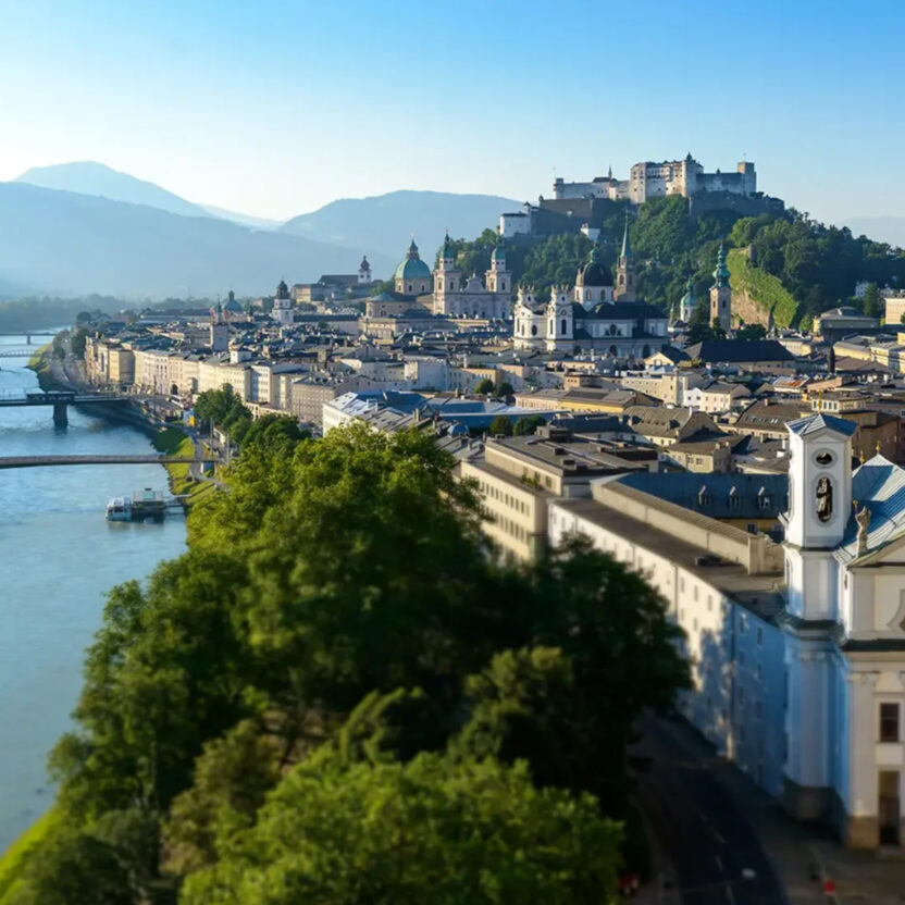 Foto von der Stadt Salzburg von oben. Zu sehen ist die Salzach, der Mönchberg mit Festung, der Salzburger Dom und die Altstadt.