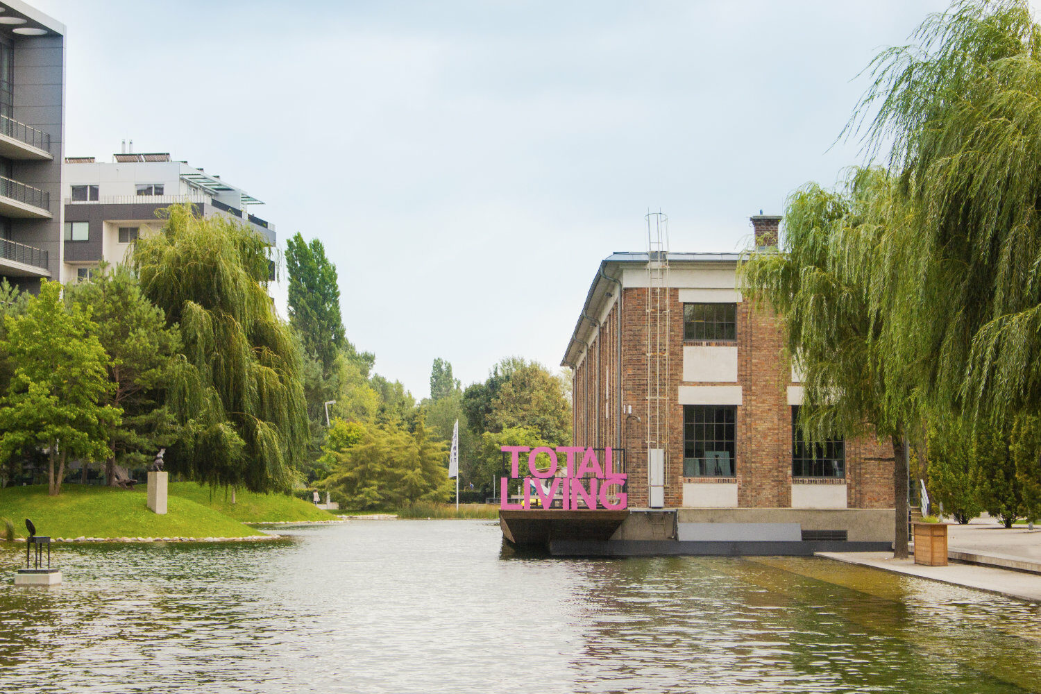 Loftgebäude am Wasser mit viel Grün in der Umgebung.