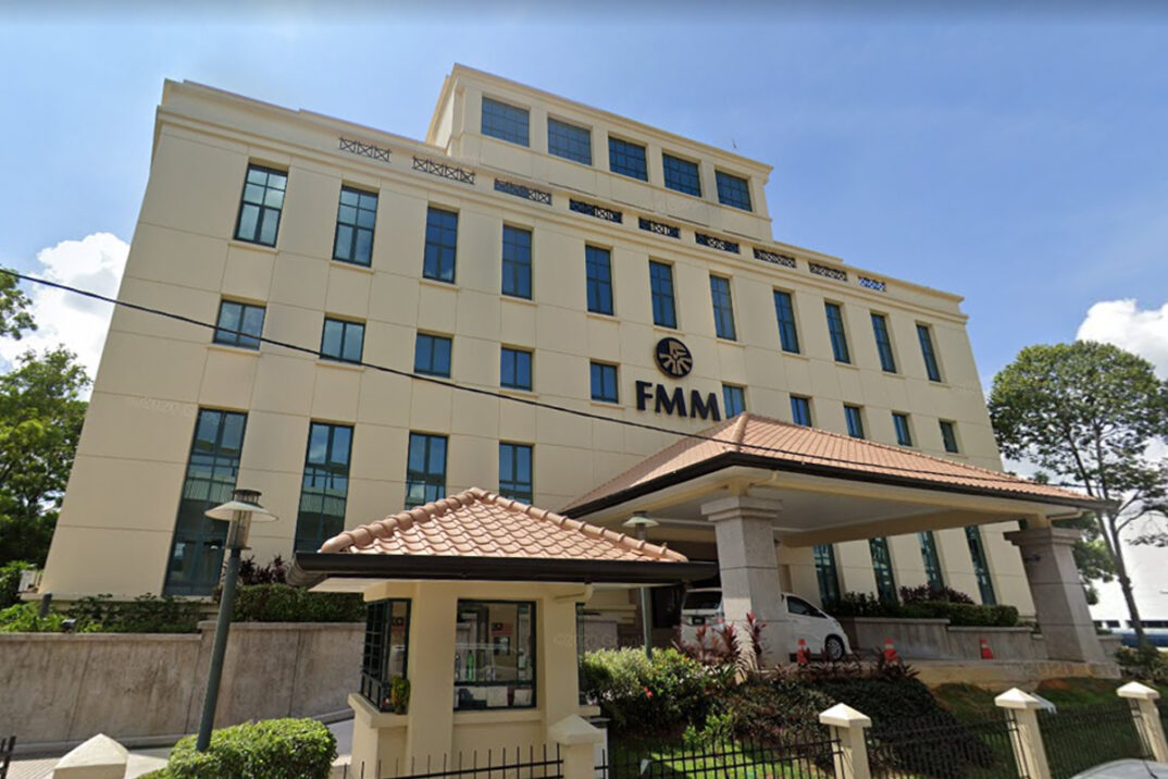 A four-story beige building with the acronym "FMM" displayed on the front, featuring large windows, a tiled roof entrance, and landscaped surroundings. This venue regularly hosts events like the valantic Manufacturing Seminar.