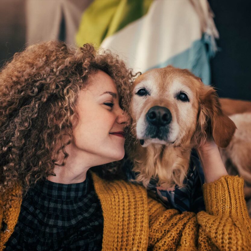 curly woman cuddling with her golden retriever dog