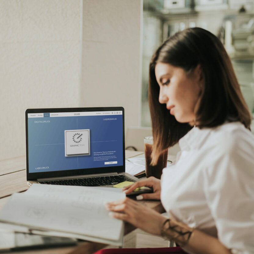 Vrouw die bladert in een boekje langs een computer scherm