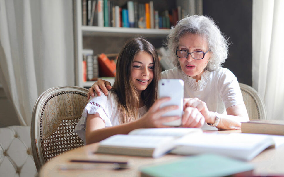 Enkelin und Großmutter nutzen auf dem Smartphone eine EAA-konforme Plattform oder einen barrierefreien Onlineshop