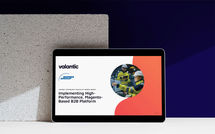 A tablet displays a presentation titled "Implementing High-Performance, Magento-Based B2B Platform" with logos of Valantic and NORMA GROUP, alongside an image of workers in safety gear.