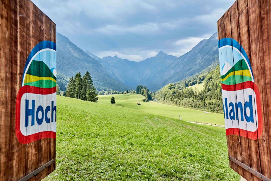 Offenes Tor mit Hochland Schriftzug und Blick in Berglandschaft