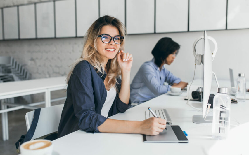 Beautiful female office worker carrying out administrative work for company. Indoor portrait of cute blonde student doing homework with asian universuty friend.