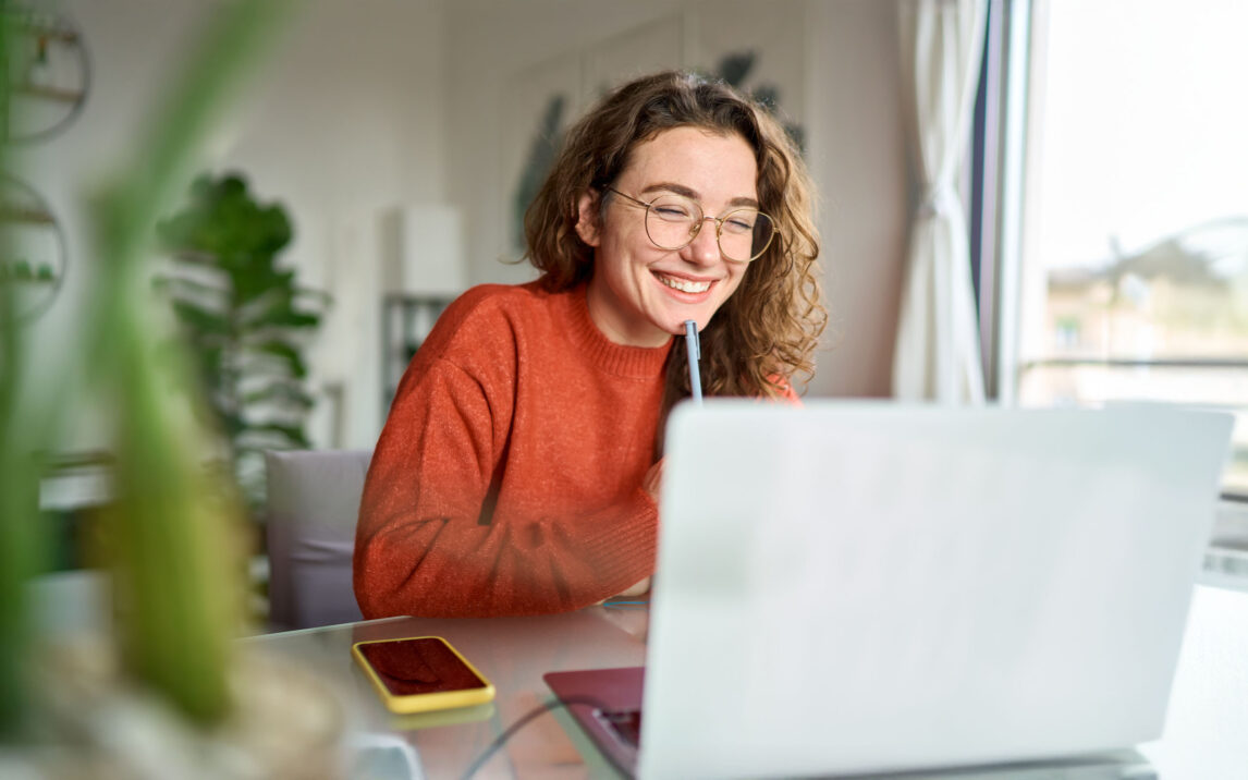 Young woman using laptop watching webinar at home