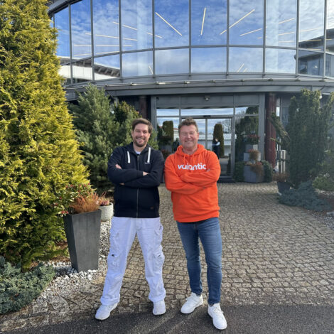 Alexander Mohr-Miesler and Marco Kahler standing with arms crossed in front of a contemporary glass building.