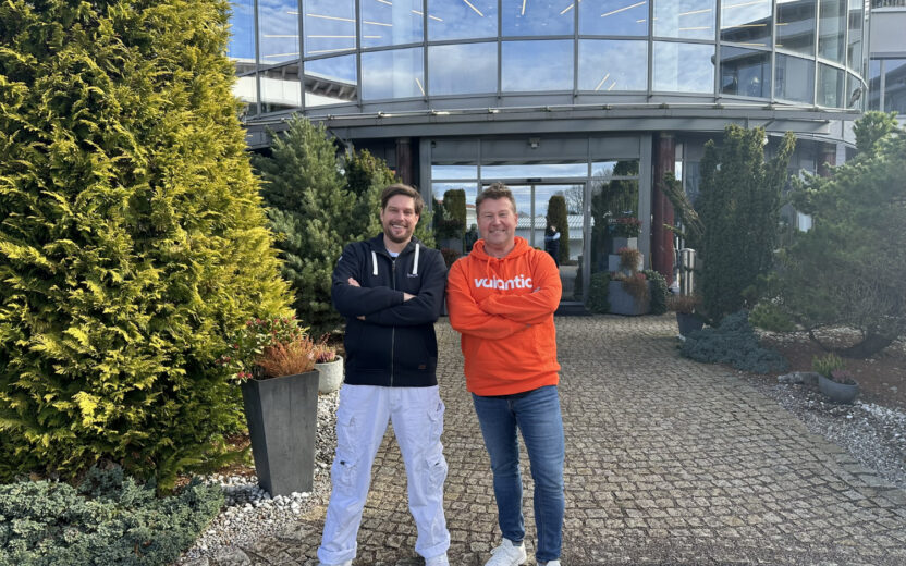 Alexander Mohr-Miesler and Marco Kahler standing with arms crossed in front of a contemporary glass building.