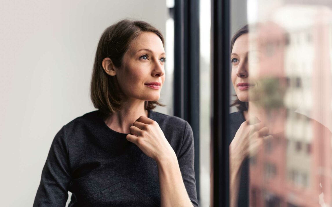 thoughtful businesswoman looking through window