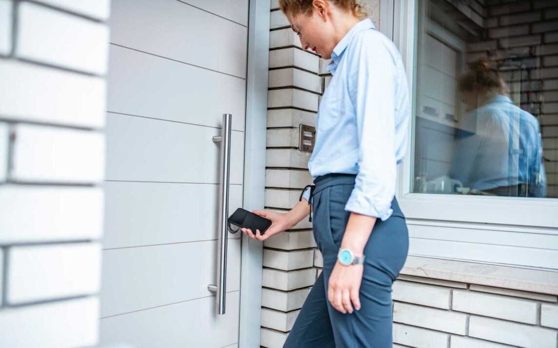 woman entering her home using smartphone