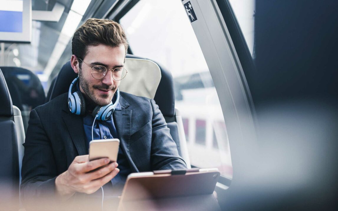 businessman in train with cell phone headphones and tablet