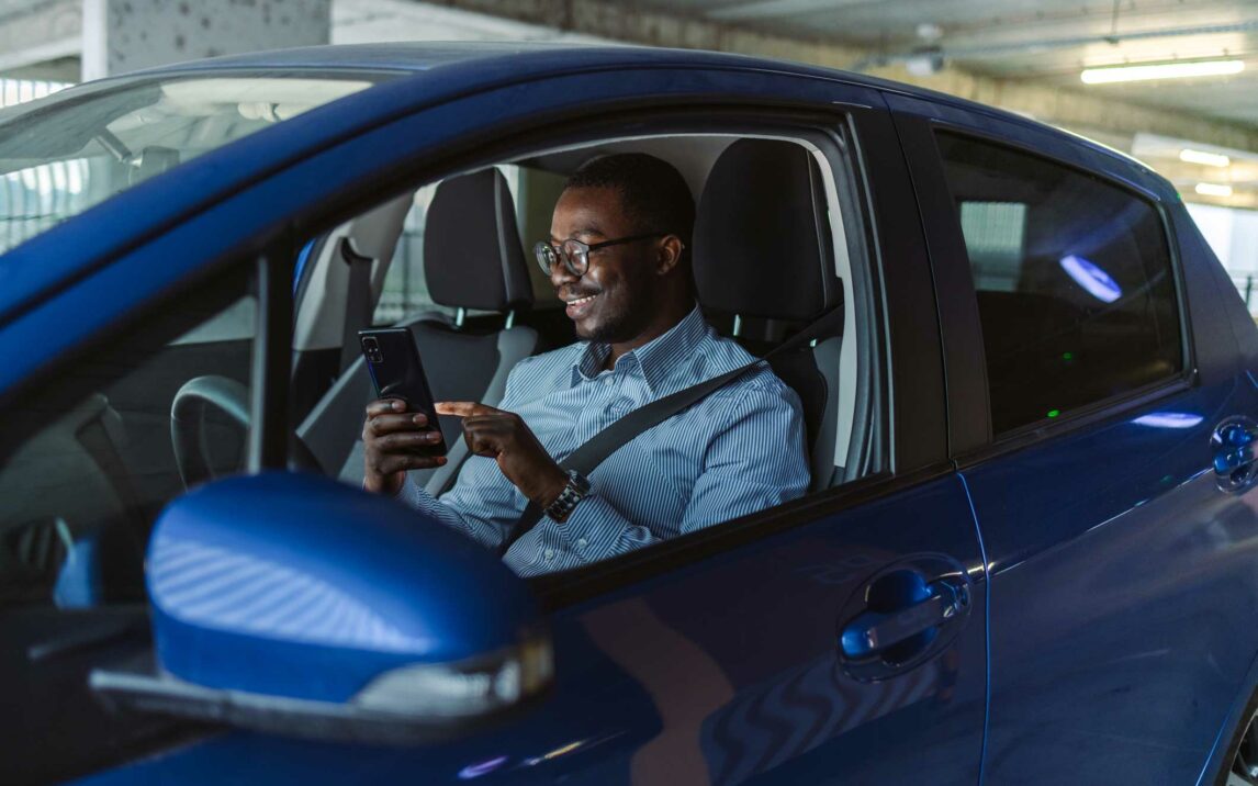 african american man using smart phone in the car