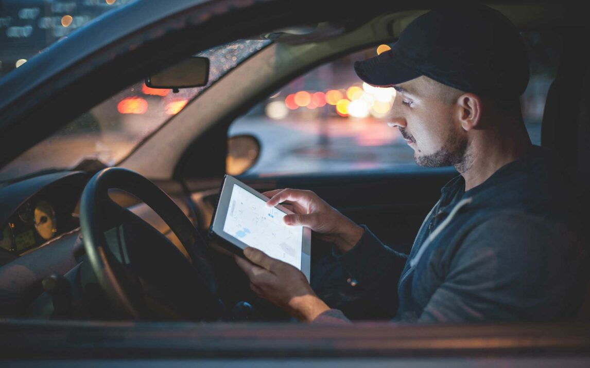 man using digital tablet in his car