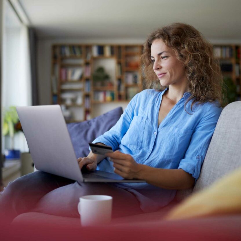 smiling woman doing online shopping on laptop at home