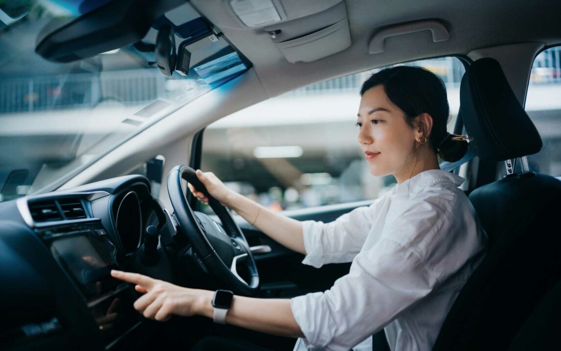 young woman sitting in car and touching screen