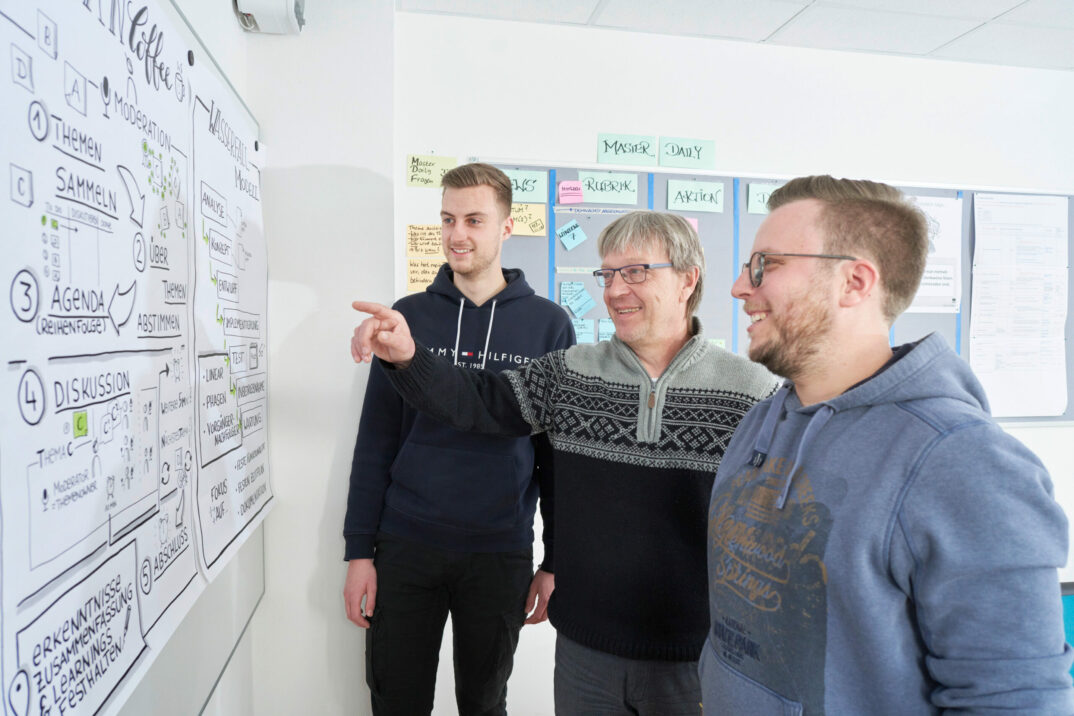 Three colleagues in a workshop situation brainstorming on a pinboard