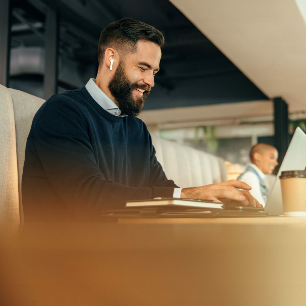 Cheerful young businessman working on his laptop in a co-working space.