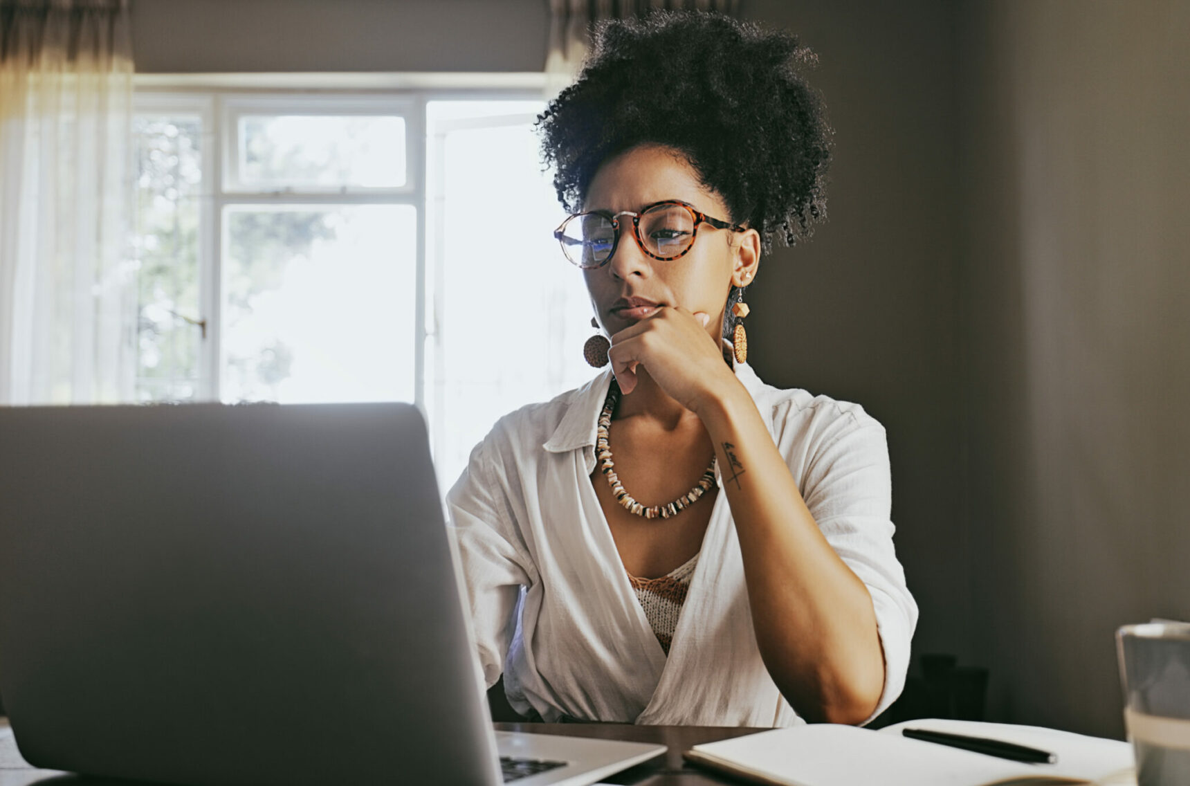 Woman thinking, planning, online research and brainstorming ideas on her laptop