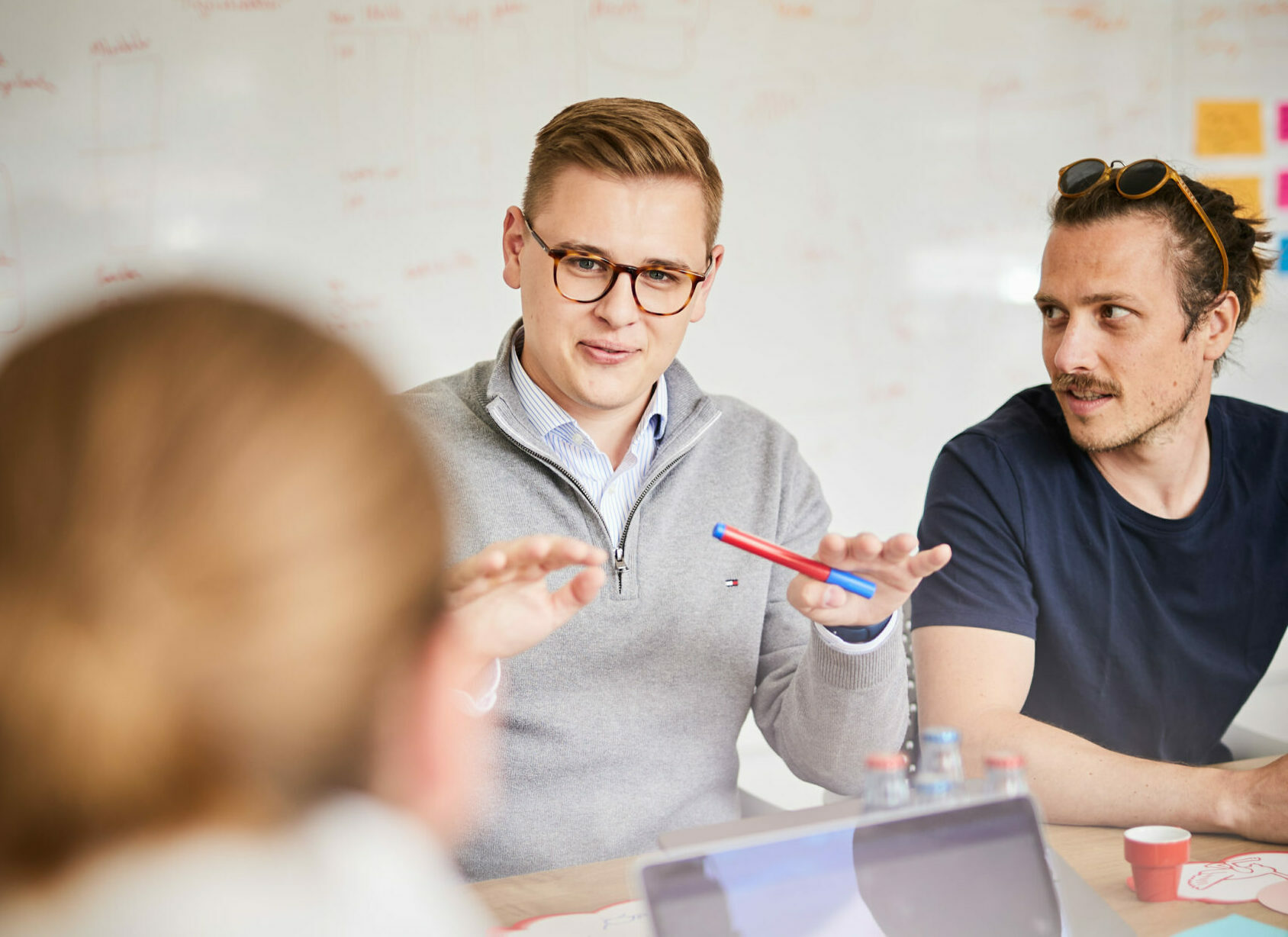 Ein Mann der seinen beiden Kollegen im Meeting eine Strategie erklärt.