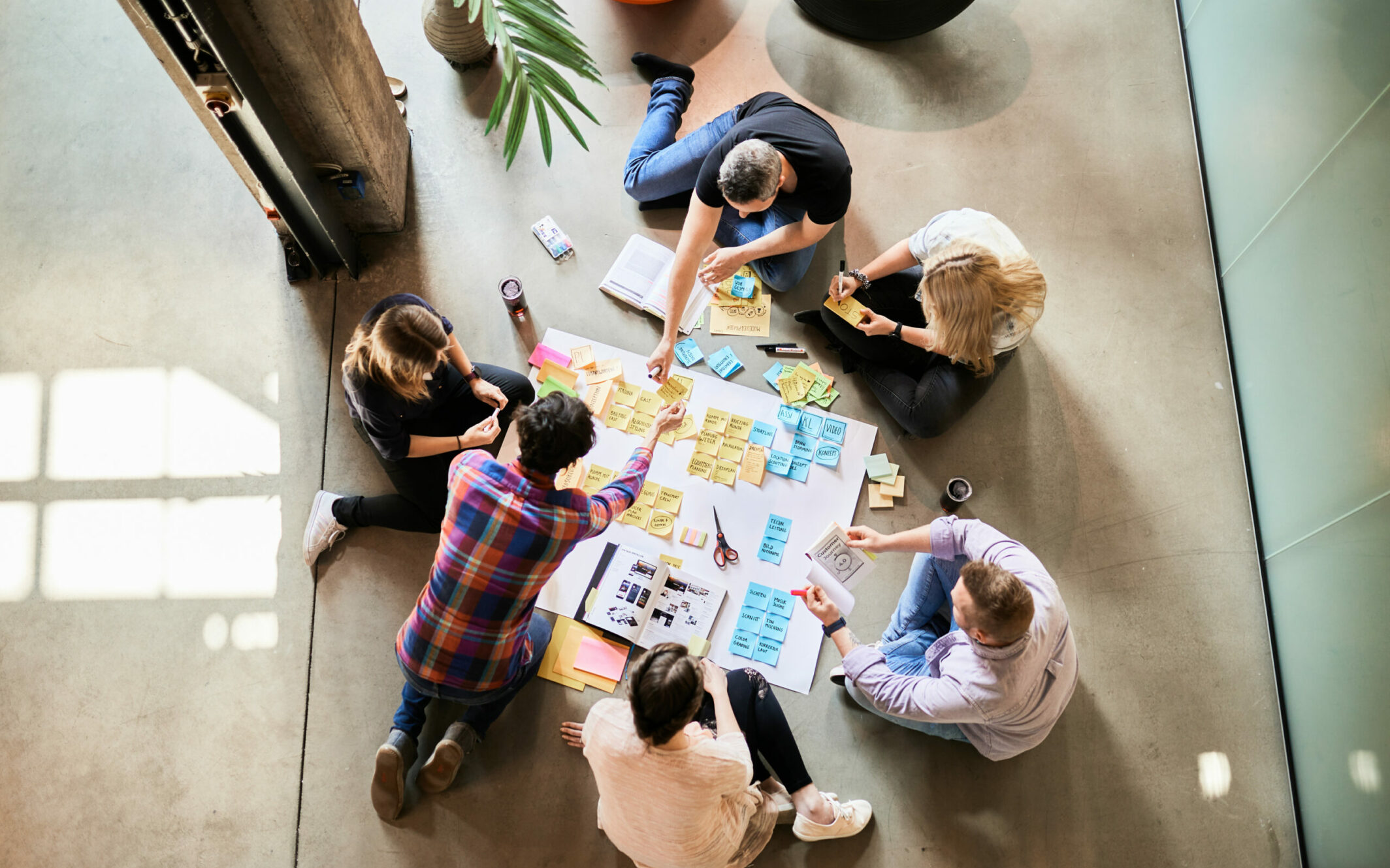 Six colleagues preparing a white poster with Post-Its for a presentation.