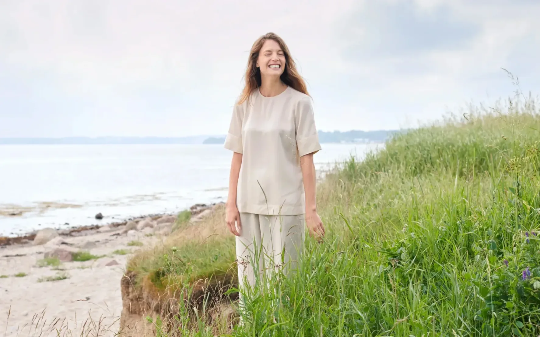 Foto von einer glücklichen Frau in den Dünen.