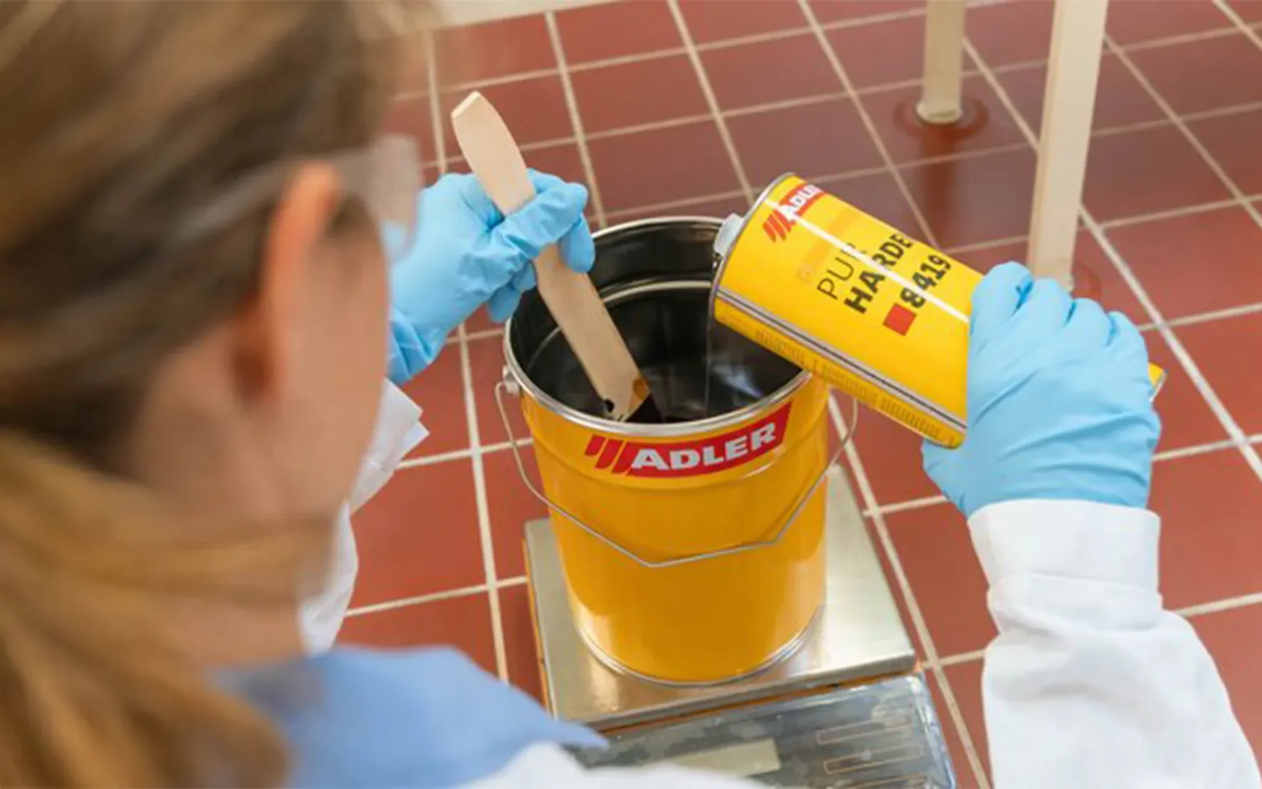 Bild von einer gelben Adler-Lacke-Dose mit dem roten Adler-Logo, aus der ein kleines Bonsai-Bäumchen wächst. Der Hintergrund ist gelb