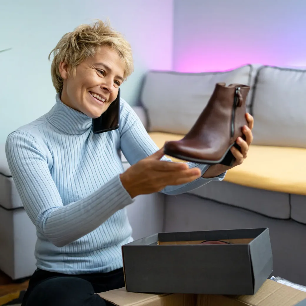 A woman is happy about her new shoes bought online. She is talking on her phone