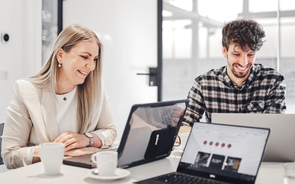 Zwei valantic Austria Mitarbeiter*innen arbeiten an ihren Laptops.